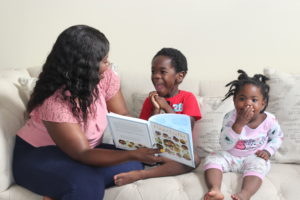 mother and children laughing while reading book