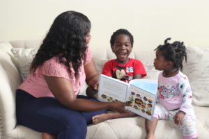 little boy and little girl pointing to book while woman reads the book