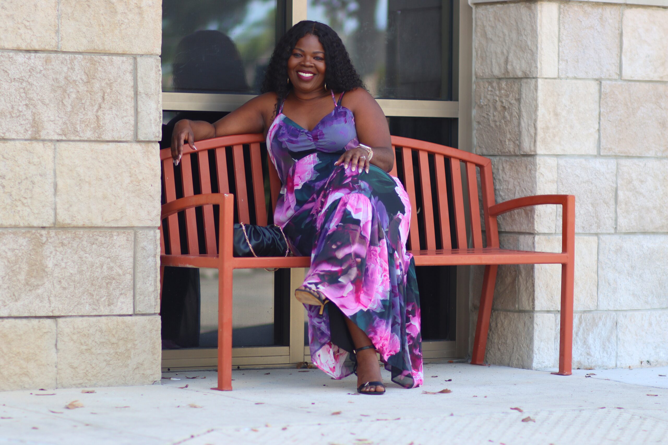 Belinda Merrin seated, smiling, wearing a floral dress